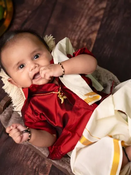 A sweet baby boy dressed in a traditional silk shirt and veshti. This type of portrait is perfect for milestones like the Annaprasana (first rice-eating ceremony) or simply to celebrate cultural heritage.