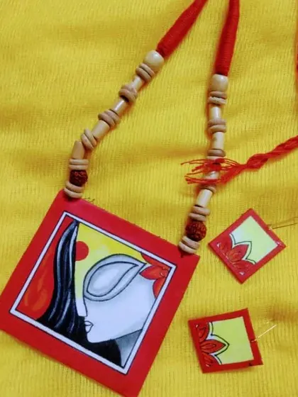 A beautiful hand-painted fabric necklace featuring a serene, artistic face. This wearable art piece is lightweight and comes with matching earrings.