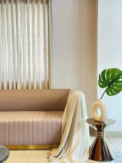 A detail shot of a fluted sofa with a brass base, designed for the Casa Creations showroom. The combination of the soft pink fabric, metallic finish, and the monstera leaf accent creates a look of modern, subtle luxury.