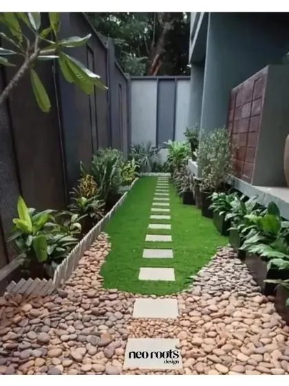 A narrow garden path is given a Zen-inspired treatment with a central strip of grass and stone pavers, bordered by smooth river pebbles. This design creates a clean, linear, and meditative walkway.