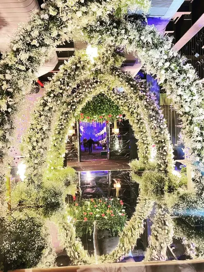 A stunning floral archway made entirely of baby's breath and white roses, creating a dreamy, cloud-like entrance for an engagement party.