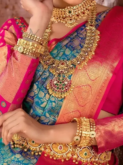 A close-up shot of a model wearing a full antique gold bridal set, including choker, haram, vaddanam, and vanki (armlets).