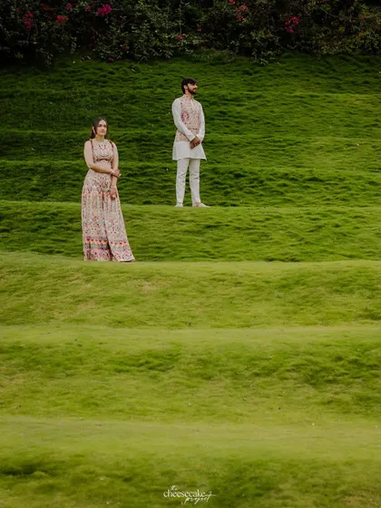 An artistic, minimalist portrait of the couple standing on terraced green lawns.