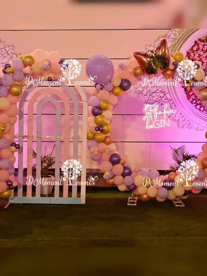 A circular balloon photo frame in pastel colors with a "Let the fun begin" sign, perfect for capturing memories at a butterfly-themed party.