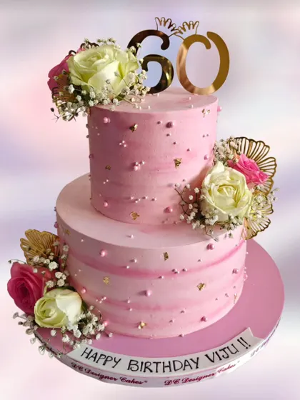 A beautiful two-tier pink cake for a 60th birthday. This design uses fresh flowers and a touch of gold leaf for a graceful and celebratory feel.