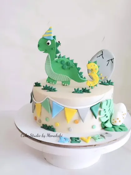For a little dinosaur lover, I created this cute dinosaur themed cake. It features a friendly green dino in a party hat, a hatching egg, and colorful bunting.