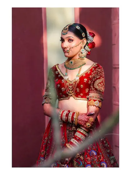 An artistic portrait of the bride, partially framed by foliage. This creative composition adds a natural and soft element to her bridal look.
