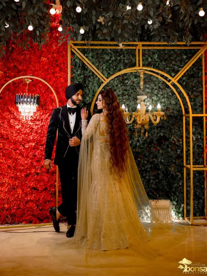 A full-length portrait of the couple against a dramatic red and green floral wall, a popular trend in wedding decor.