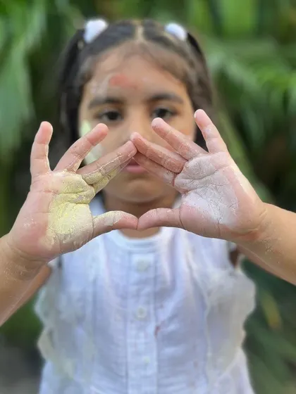 A heart shape made with hands dusted in my natural yellow and white clay powders for Holi.