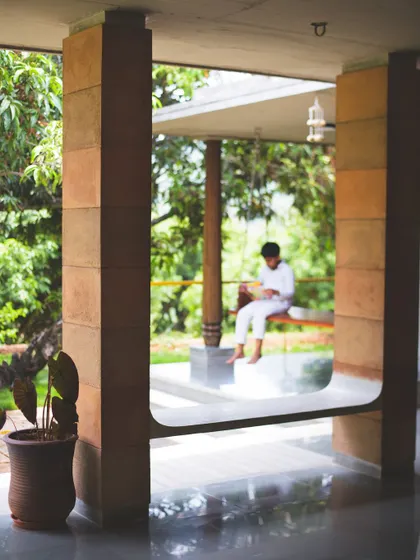 A framed view from the interior of "Aamra" looking out to the 'Jagli' or verandah. The U-shaped cutout in the CSEB pillar is a subtle design gesture that creates a visual connection between spaces.