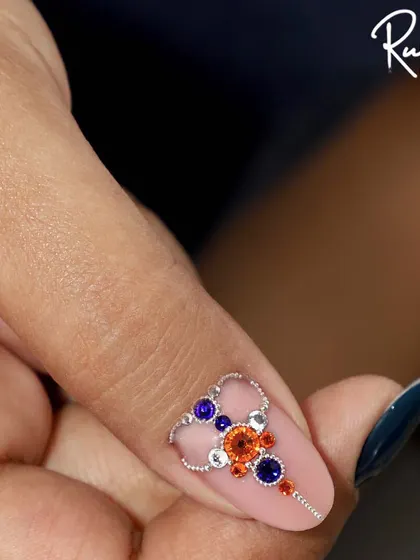 A different angle of the multi-colored crystal jewelry piece, showing how it sits elegantly on the nail.