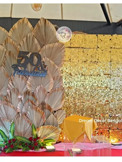 A '50 & Fabulous' backdrop combining a gold sequin wall with dried palm leaves. This design is modern, stylish, and perfect for a milestone celebration.