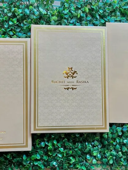 This is a classic, understated wedding invitation suite in a cream and gold palette. The design uses a subtle embossed pattern on the card and envelope, with the couple's names and a traditional motif stamped in gold foil.