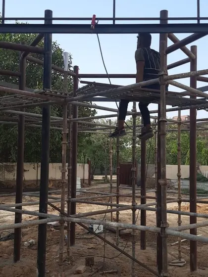 A worker on the scaffolding of a play structure, showing the complexity of the fabrication process.