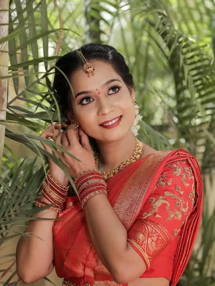 A candid, smiling shot of the bride amidst greenery.