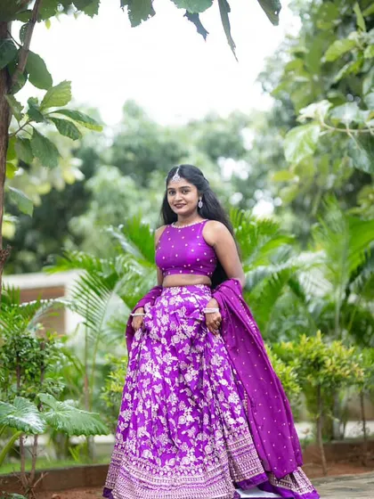 A happy client posing in her vibrant purple lehenga. I love how the color pops against the green background.