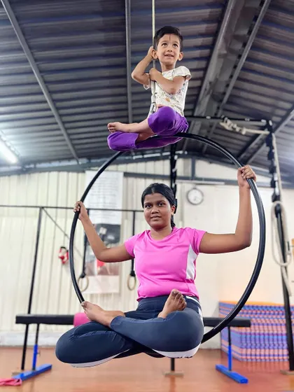 Building confidence together. An older student provides a stable base on the aerial hoop while a younger one perches on top, a perfect example of the mentorship and trust in our studio.