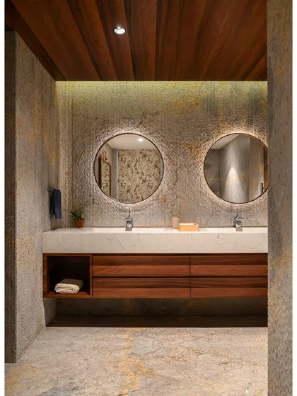 This rustic master bathroom is one of our favorite spaces. It features a double vanity with a custom wood cabinet and twin mirrors set against a wall of rough, textured marble.