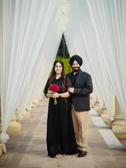 A simple and elegant pre-wedding photo in a beautiful white colonnade. The bride holding a bouquet of red roses adds a perfect pop of color.