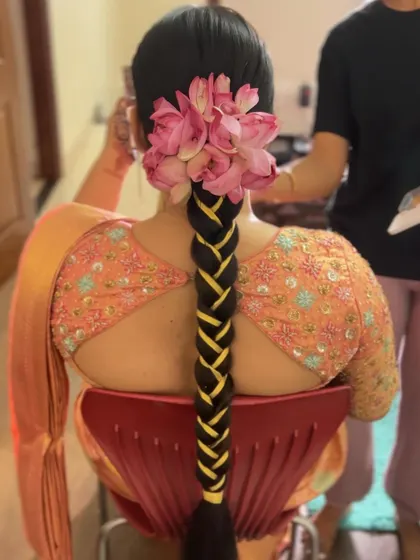 A closer look at the neat ribbon work on a traditional braid, topped with fresh lotus petals. Precision is key for this classic South Indian bridal hairstyle.