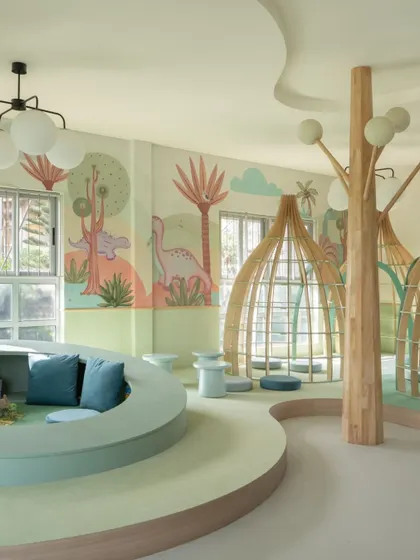 The nursery library is a world of its own, with curved, multi-level seating, tree-like columns, and dinosaur-themed murals. Every element is designed to spark imagination and make reading an exciting adventure.