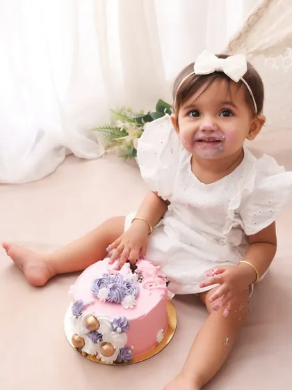 A sweet smile and a messy face. This little girl is enjoying her first birthday cake in our lovely boho-themed setup. The combination of the pink cake and her white dress is simply adorable.