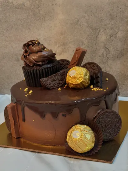 This chocolate cake is a feast for the eyes and the palate, topped with Ferrero Rocher, Oreos, a chocolate cupcake, and a rich ganache drip.