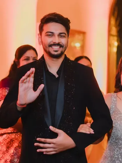 The groom waving to guests as he enters the reception with his bride, a candid shot full of happiness.