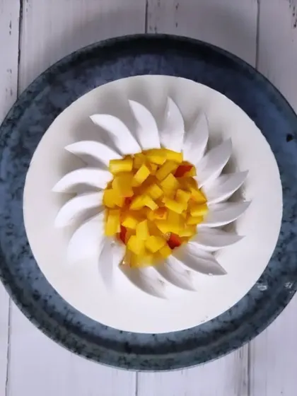 A beautifully designed mango mousse cake, with the cream piped to resemble a flower and a center filled with diced mango. It's a visual and culinary delight.