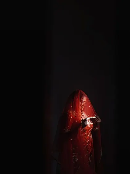 A minimalist and highly artistic composition. The bride, a small beacon of red in a vast expanse of darkness, creates a powerful feeling of anticipation and solitude.