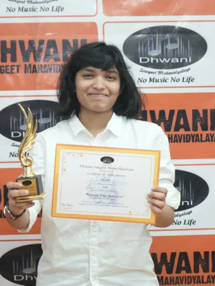 A student smiles proudly with her certificate and trophy.
