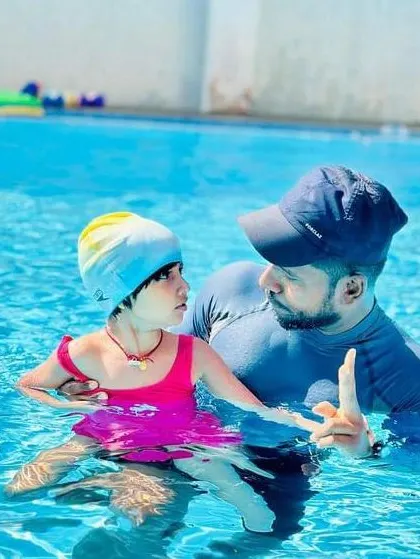 A coach gives gentle instructions to a young girl in the water. Our teaching method is based on clear communication and patient guidance.