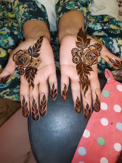 A bold and artistic take on floral henna, with large rose motifs on the palms and leafy patterns on the fingers.