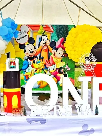 A classic Mickey Mouse Clubhouse theme for a first birthday. This setup is packed with color and fun, featuring Mickey, Minnie, Goofy, and a large "ONE" sign.