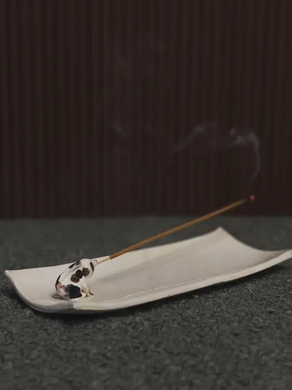 A minimalist incense holder featuring a tiny, spotted dog. The simple, elegant design allows the focus to be on the whimsical animal figure.