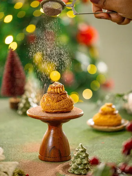 An action shot of powdered sugar being dusted over a Christmas pastry, adding a touch of magic and motion to the scene.