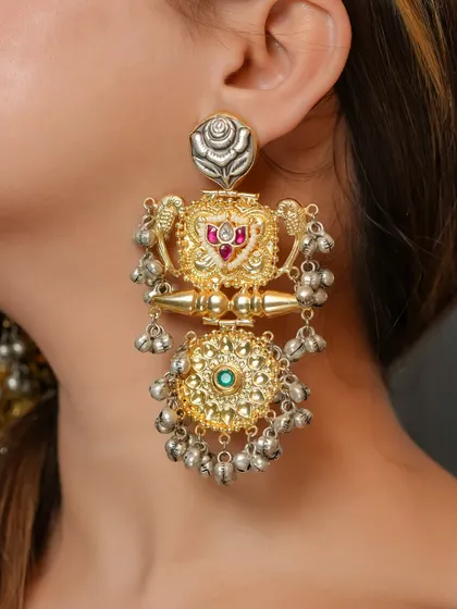 A detailed view of another unique dual-tone earring, showcasing a floral stud and dangling silver ghungroos.