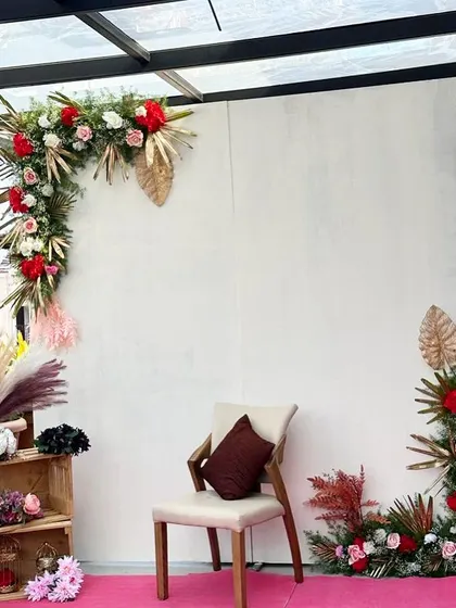 This simple yet elegant Mehendi setup features a stylish asymmetrical floral arch against a clean white backdrop, perfect for intimate, modern celebrations.