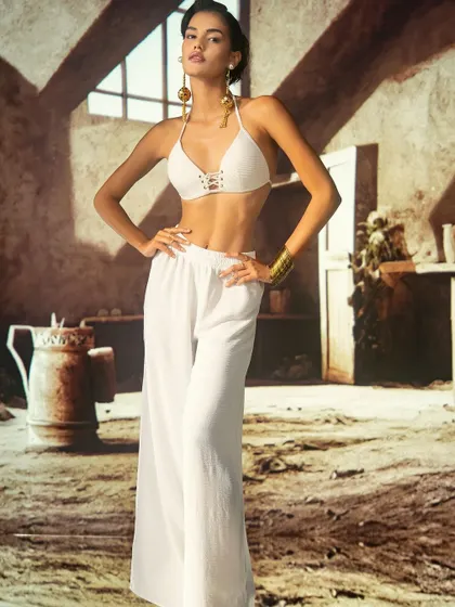 A rustic, sun-drenched interior scene created with projection. This technique provides a warm, earthy backdrop that complements the simple, clean lines of the white outfit.
