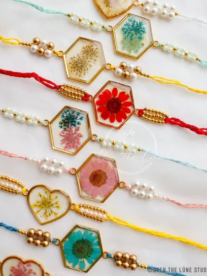 A close-up of the different shapes and flowers in my Rakhi collection, including hearts and hexagons. Each one is finished with pearl and gold-colored beads.