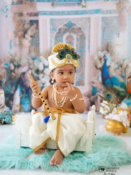A pensive moment for our little Krishna. Holding his flute, he looks like he is contemplating a divine melody in this beautiful Janmashtami setup.