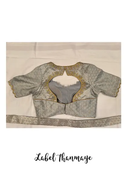 A grey brocade blouse with a cut-out back, outlined with delicate gold embroidery.
