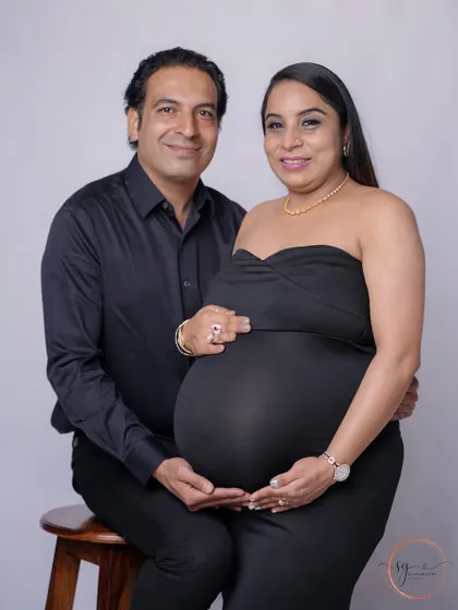 A beautiful, classic portrait of the expecting couple looking towards the camera. Their coordinated black outfits create a timeless and sophisticated look.