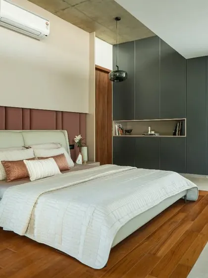 A contemporary bedroom in the Long House, featuring a padded headboard, sleek built-in storage, and a minimalist color palette.