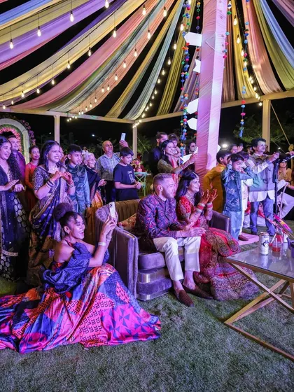 The energy of a Sangeet is infectious. Here, the couple and their guests enjoy the performances under a vibrant canopy of lights, creating a memory filled with music, laughter, and shared joy.