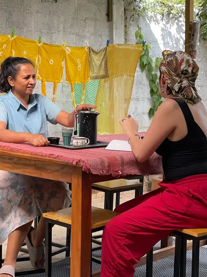 A candid shot of a conversation at our outdoor cafe table, with naturally dyed yellow fabrics hanging to dry in the background. We cherish these moments of connection and shared ideas.