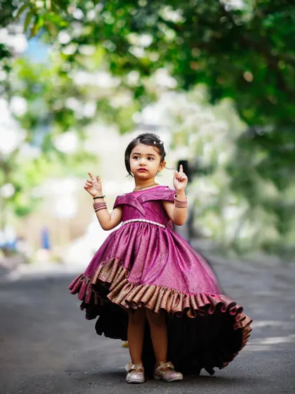 A little princess in a stunning purple gown for her third birthday shoot. This outdoor shot captures her elegance and charm.
