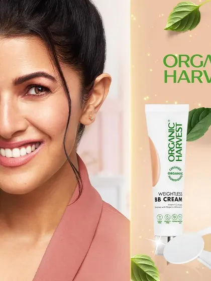 A campaign photograph featuring actress Nimrat Kaur for Organic Harvest. This shot combines a warm, approachable portrait with product imagery for their BB cream and compact, creating an authentic celebrity endorsement for a natural cosmetics brand.