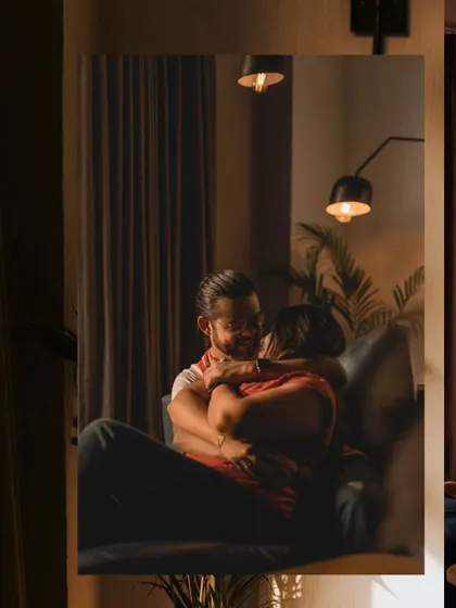 A beautifully framed shot of a couple embracing on a couch, seen through a doorway. This creates a sense of intimacy and quiet observation.