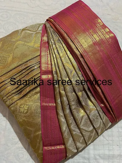 A beautiful gold and pink silk saree, folded to protect its delicate weave and keep it ready for the next event.